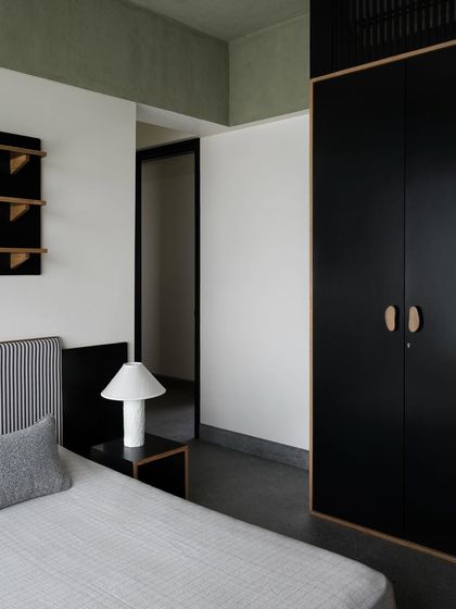 A son's bedroom featuring a sleek, black wardrobe. I design storage to match the personality of the room, and this minimalist wardrobe provides a strong, graphic element against the softer textures.