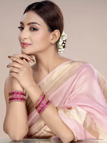 A model displays a set of magenta-colored traditional bangles. The simple, direct pose ensures the product is clearly visible, perfect for catalogue photography.