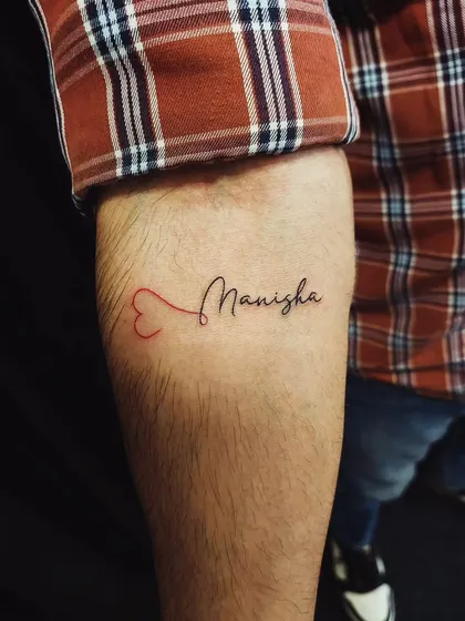 A name tattoo where the script flows out of a red heart. This is a creative way to symbolize that a person is always in your heart.