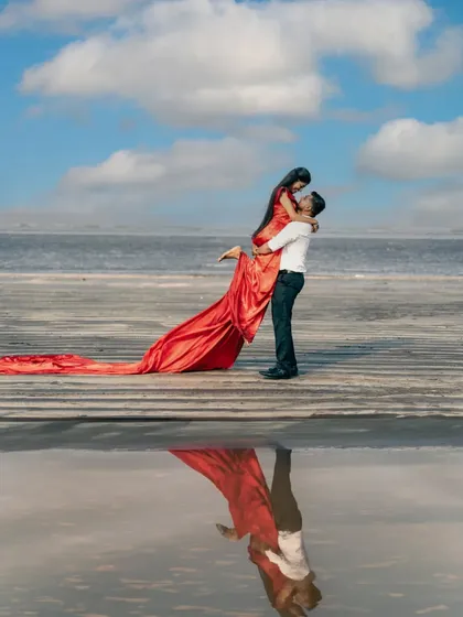 A breathtaking pre-wedding moment captured on the beach, with the couple's reflection creating a perfect mirror image. This shot combines romance, nature, and a touch of cinematic magic, ideal for couples looking for a dramatic beach pre-wedding photoshoot.