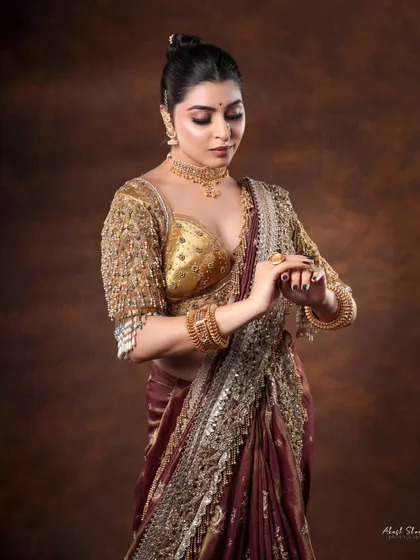 A classic pose showcasing the intricate embroidery on the golden blouse and the detailed craftsmanship of the traditional jewelry.