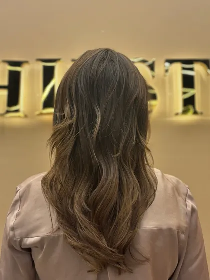 The back of a client's hair after a color service, styled with soft waves to show off the subtle, natural-looking highlights.