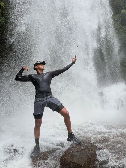 A trekker strikes a pose on a rock in the middle of a powerful stream at Kodachadri.
