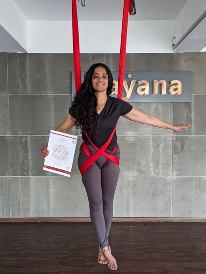 A newly certified teacher poses gracefully in the hammock, certificate in hand.