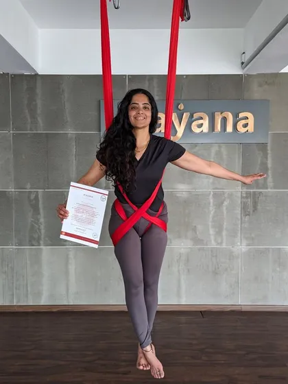 A newly certified teacher poses gracefully in the hammock, certificate in hand.