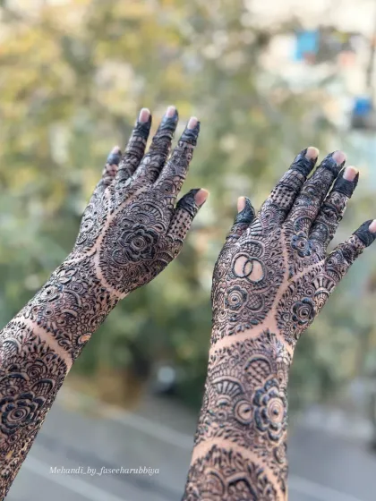 A close-up of Nabeela's floral engagement henna, showing the interlocking rings symbol on her palm.