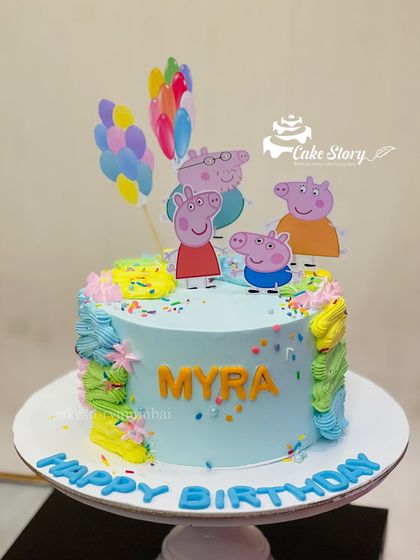 A cheerful Peppa Pig cake for Myra's birthday. This light blue cake is decorated with colorful sprinkles, the Peppa Pig family, and a bunch of balloons.