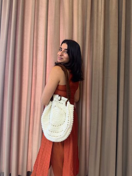 A side view of me with our round tote bag. The unique circular shape and contrasting brown handle make it a really special piece.