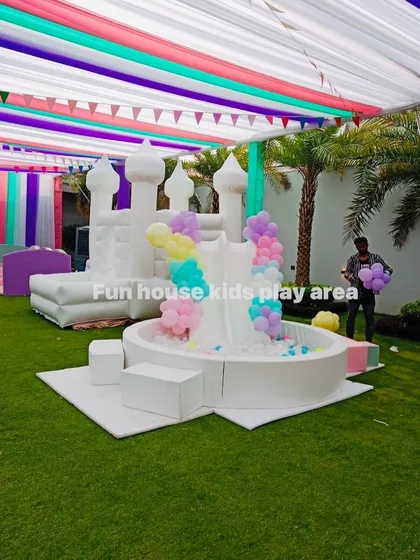 A beautiful outdoor setup combining our white bounce castle with a white ball pool and double slide, decorated with pastel balloons.