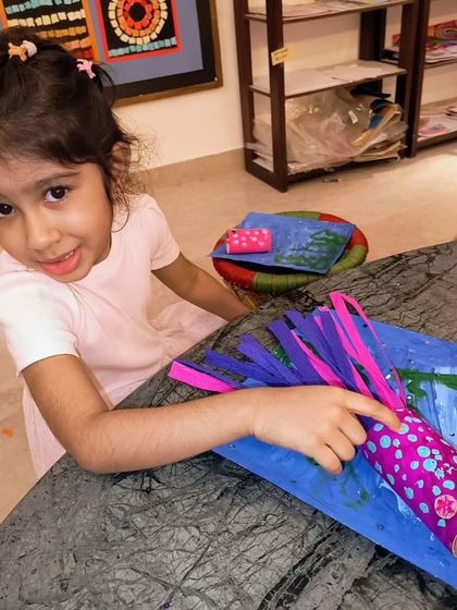 This little girl is carefully adding the final tentacles to her paper jellyfish, a fun craft that combines painting and paper sculpture.