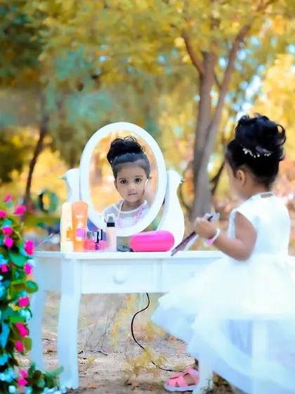 An outdoor makeup-themed shoot with a little girl at a vanity table in a park setting.