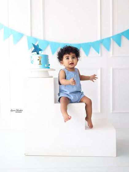 A post-cake smash portrait. This little guy is proud of his work, sitting happily next to his blue birthday cake.
