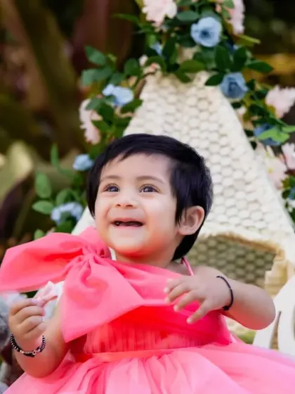 A bright and happy smile from a little girl in a pink dress, surrounded by outdoor props.