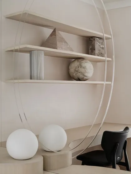 A close-up of the unique bookshelf in the daughter's room. The transparent acrylic support creates the illusion that the shelves and the stone objects are floating, adding a magical touch to the space.