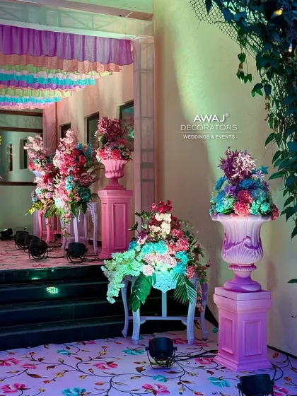 The entrance to the event, with a floral carpet and large pastel floral arrangements in ornate urns.