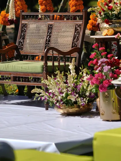 A detail shot from the Malabari-themed Haldi, showing the traditional wooden seating and brass pots filled with flowers.