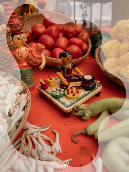 A close-up of a Channapatna toy depicting a woman cooking, set amongst fresh vegetables on the spice cart. This playful detail adds a narrative element to the decor, celebrating the theme of local life.