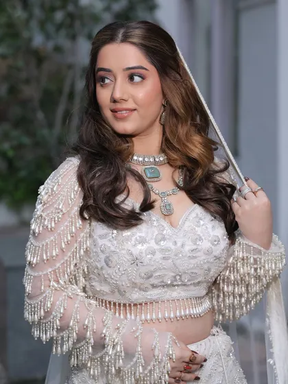 A beautiful portrait of our bride-to-be. The natural, soft glam makeup enhances her features, and the voluminous waves add a touch of glamour to her white ensemble.