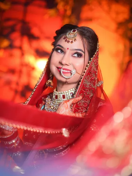 A joyful bridal portrait with a beautiful smile, using a red dupatta to frame the shot.