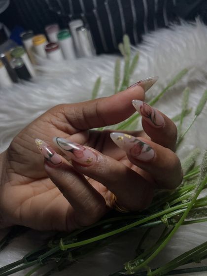 This design showcases delicate, hand-painted floral art on long, translucent nail extensions. The subtle gold foil flakes add a touch of luxury, making this a beautiful option for bridal or engagement nails.