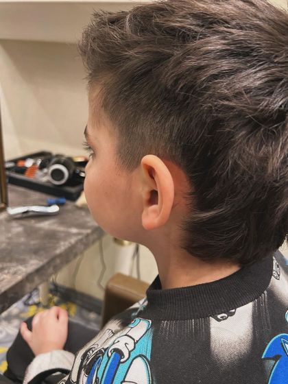 The side view of this kid's mullet shows the clean fade on the sides, which contrasts with the textured length on top and in the back.