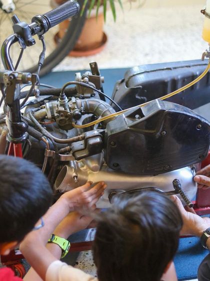 A group of kids works together to reassemble a motorcycle engine. This kind of collaborative problem-solving is a huge part of the tinkering experience.