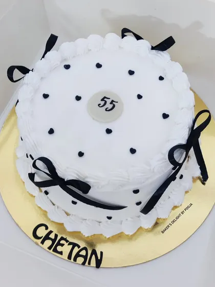A simple yet elegant vintage-style cake in black and white for a 55th birthday, decorated with polka dots and delicate ribbon bows.