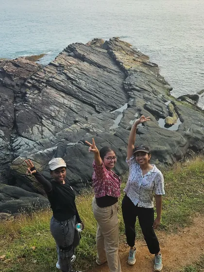Three friends posing on the rocky cliffs of Gokarna, with the beautiful sea in the background.
