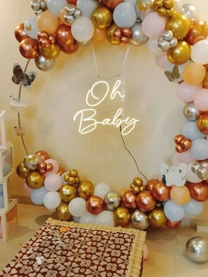 An "Oh Baby" themed decoration with a circular balloon arch in chrome colors and transparent "BABY" boxes for a modern baby shower.