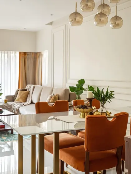 The dining area flows seamlessly from the living room. We introduced a pop of color with these rich, burnt-orange velvet chairs, which add warmth and personality to the neutral space. The pendant lights add a touch of modern glamour.