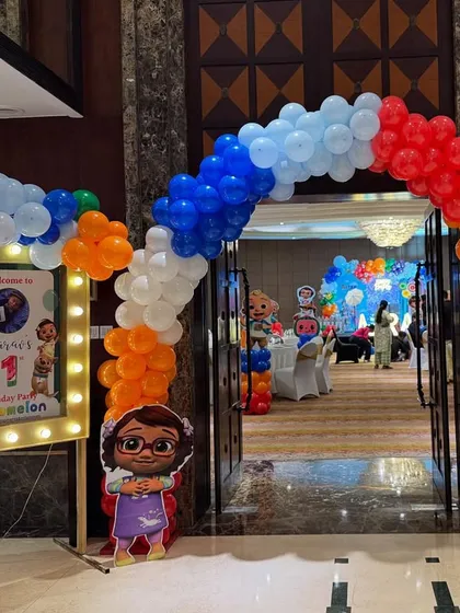 The grand entrance to Aarav's Cocomelon party, with a multi-colored balloon arch and a welcome sign in a lit-up frame.