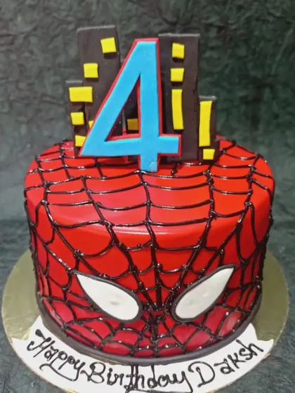 A striking Spider-Man cake with a glossy red web design and the iconic mask eyes. The city skyline at the top completes the superhero look.
