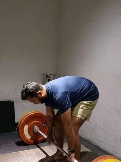 A client performing a conventional deadlift, focusing on maintaining a neutral spine and proper hip hinge mechanics.