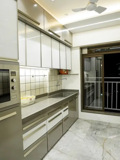 Another angle of the parallel kitchen, showing the dedicated space for the microwave oven and the well-lit sink area. The design is all about functionality and a clean look.
