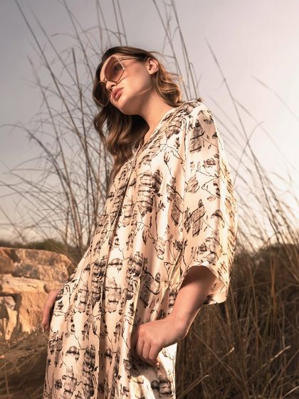 An upward-angle shot that uses the sky and grass to frame the model, creating a sense of freedom and elegance. This angle elongates the silhouette and highlights the flow of the dress.