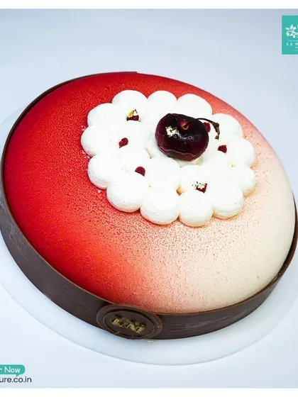 A modern take on a classic, our Black Forest Revisited cake. This entremet features a beautiful red and white velvet finish, with a fresh cherry and cream topping.