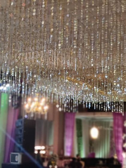 A view looking up at the dazzling ceiling decor. Thousands of shimmering silver discs and crystal strings hang down, creating a spectacular, light-catching installation.