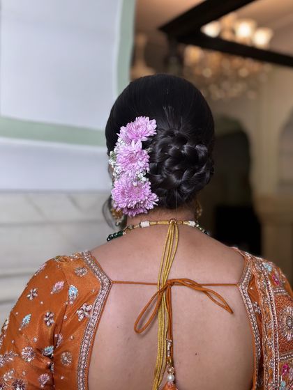 This intricate braided bun is softened with a cascade of fresh purple chrysanthemums and baby's breath. In my class, we explore how to weave braids into an updo and artfully arrange flowers for a romantic wedding hairstyle.