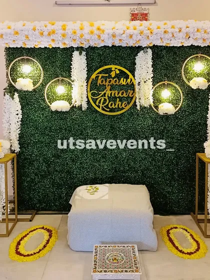 A simple and sweet baby shower setup for a home ceremony. It features a greenery wall with a custom name sign and hanging floral decorations.