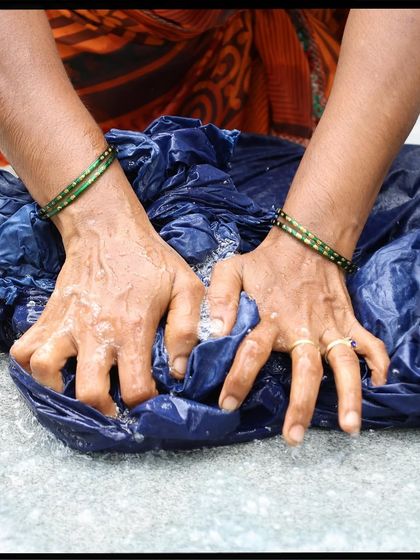 The hands of our artisan washing fabric dyed with natural indigo. This is one of the final steps in our 14-step process, ensuring the color is set and the fabric is ready for its next journey.