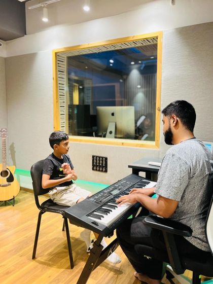 A vocal student works with his instructor at the keyboard. This shows our integrated approach to teaching, where students learn melody and harmony alongside their primary instrument.