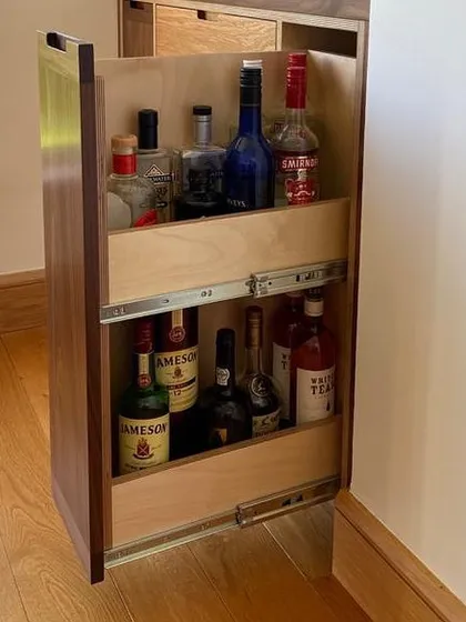 For spirits and larger bottles, I designed this full-extension pull-out drawer. It provides a sturdy, two-tiered storage solution, making every part of the cabinet easily accessible. This is a great example of custom storage for a home bar.