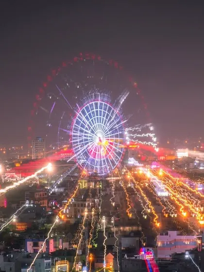 A creative zoom-burst, long-exposure shot of a Ferris wheel in Vietnam, creating an explosion of light trails.