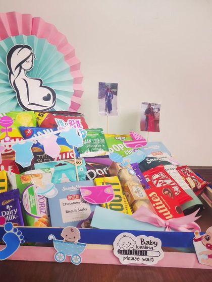 A simple and sweet hamper for a baby shower, packed with snacks and decorated with a 'Baby loading' sign. The pink and blue theme keeps the mystery alive.