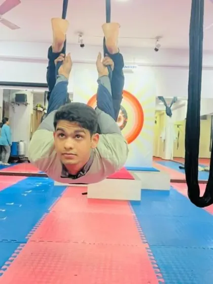 A young student enjoying the fun of aerial yoga. This inverted pose is not only playful but also helps to build body awareness and strength in a safe, supported way.