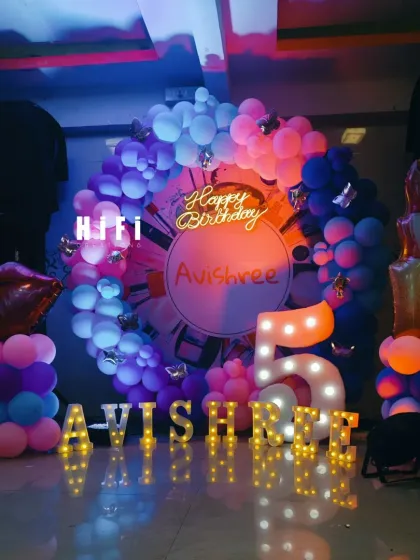 A close-up of the makeup-themed birthday party, showing the custom backdrop and light-up name.
