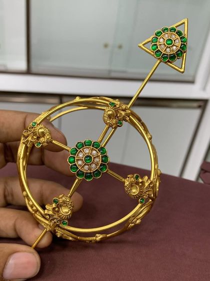 A top-down view of the green stone designer bun cover, showing the beautiful symmetry of the design. The central floral motif is surrounded by smaller floral details on the frame.