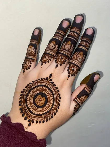 A closer look at the back-of-hand mandala design, showing the fine details within the central flower and the leaf border.