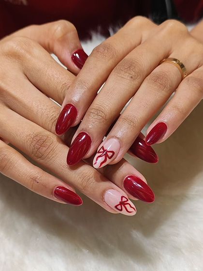 A closer look at the red bow nail art, showing the clean lines and glossy finish.
