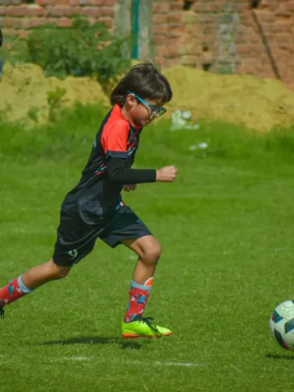 A young athlete dribbles down the field with determination, his eyes focused on the game ahead.